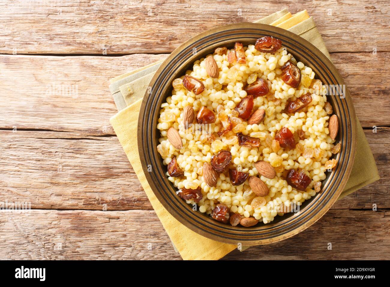 Mesfouf Qsentena Sweet Couscous mit Datteln Nuts Rosinen Nahaufnahme in einer Platte auf dem Tisch. Horizontale Ansicht von oben Stockfoto