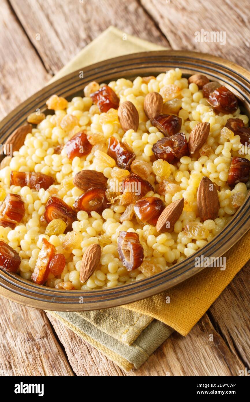 Mesfouf oder masfouf ist ein algerisches, marokkanisches und tunesisches Gericht, das süßes Couscous mit getrockneten Früchten und Nüssen in Nahaufnahme auf einem Teller auf dem Tisch serviert Stockfoto