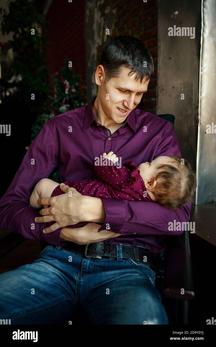 Junger hübscher Kerl, der seine kleine Tochter in den Armen hält Stockfoto