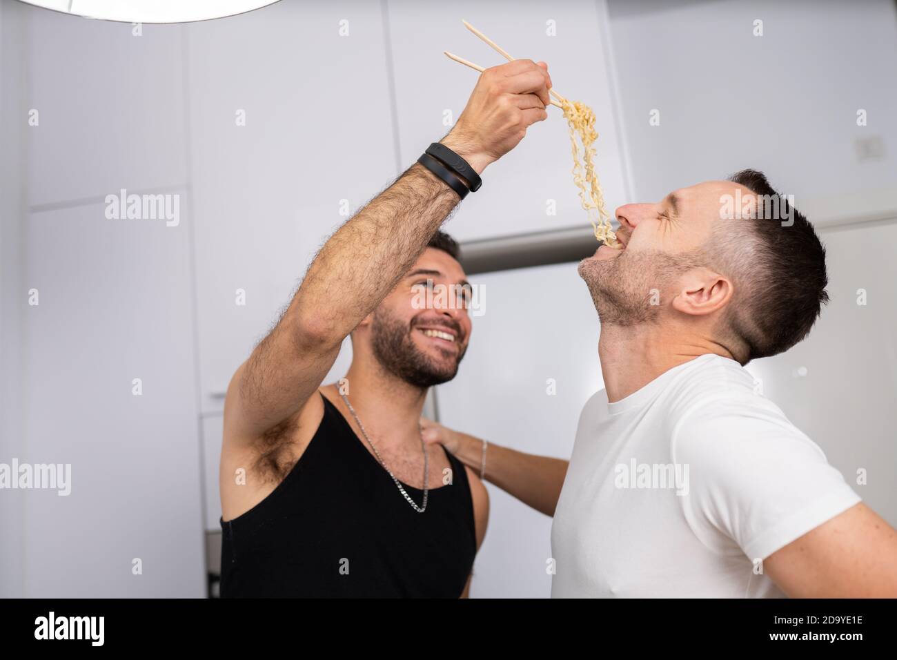 Mann Fütterung Pasta zu seinem Freund in einer lustigen Weise Stockfoto