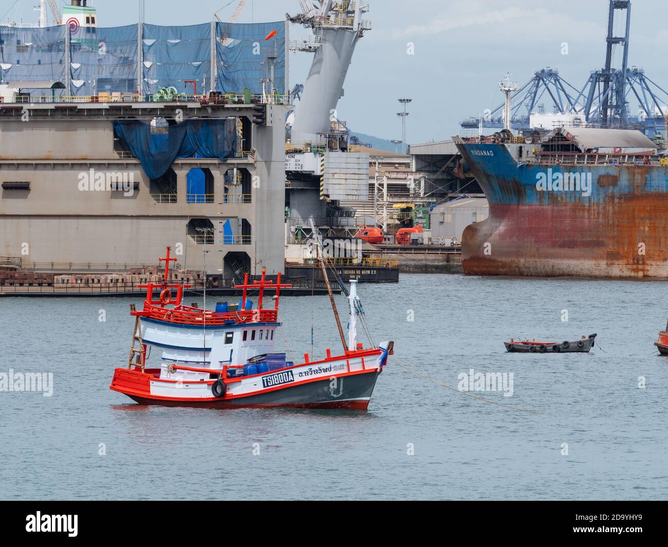 Traditionelles Fischerboot aus Holz vor einer großen Werft in Laem Chabang, dem wichtigsten Handelshafen Thailands, verankert. Stockfoto