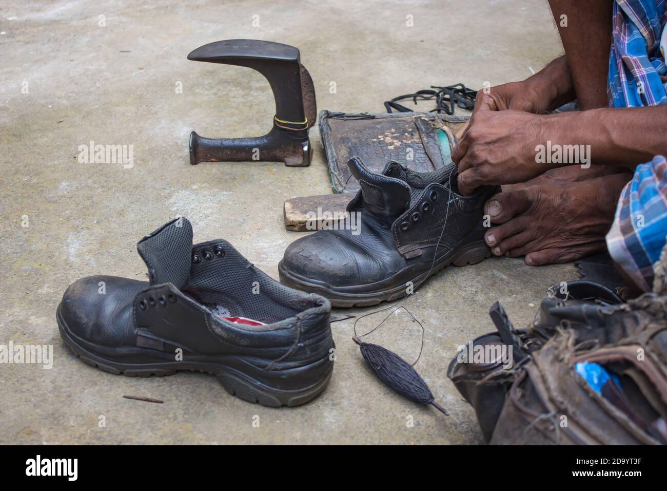 Indische lokale Schuster Reparatur Schuhe neben der Straße von Hand mit Werkzeugen in traditioneller Weise. Natürliche Schuss Darstellung der täglichen Arbeit eines regelmäßigen Schuster. Stockfoto