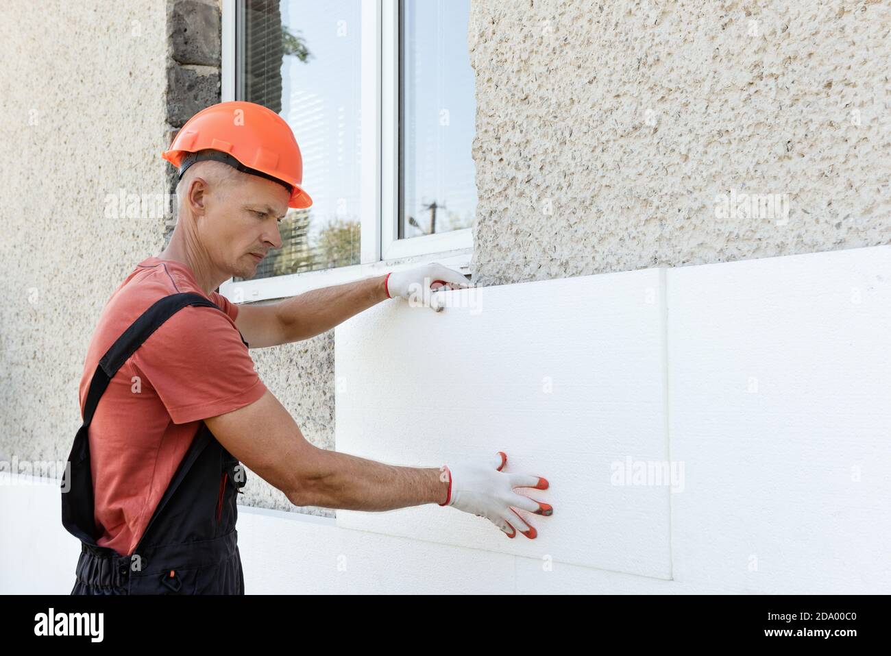 Isolierung des Hauses mit Polyfoam. Der Arbeiter installiert eine  Styroporplatte an der Fassade Stockfotografie - Alamy