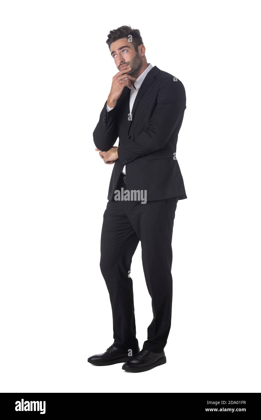 In voller Länge Porträt von jungen schönen Geschäftsmann in schwarz Anzug Denken Hand auf Kinn Studio isoliert auf weiß halten Hintergrund Stockfoto