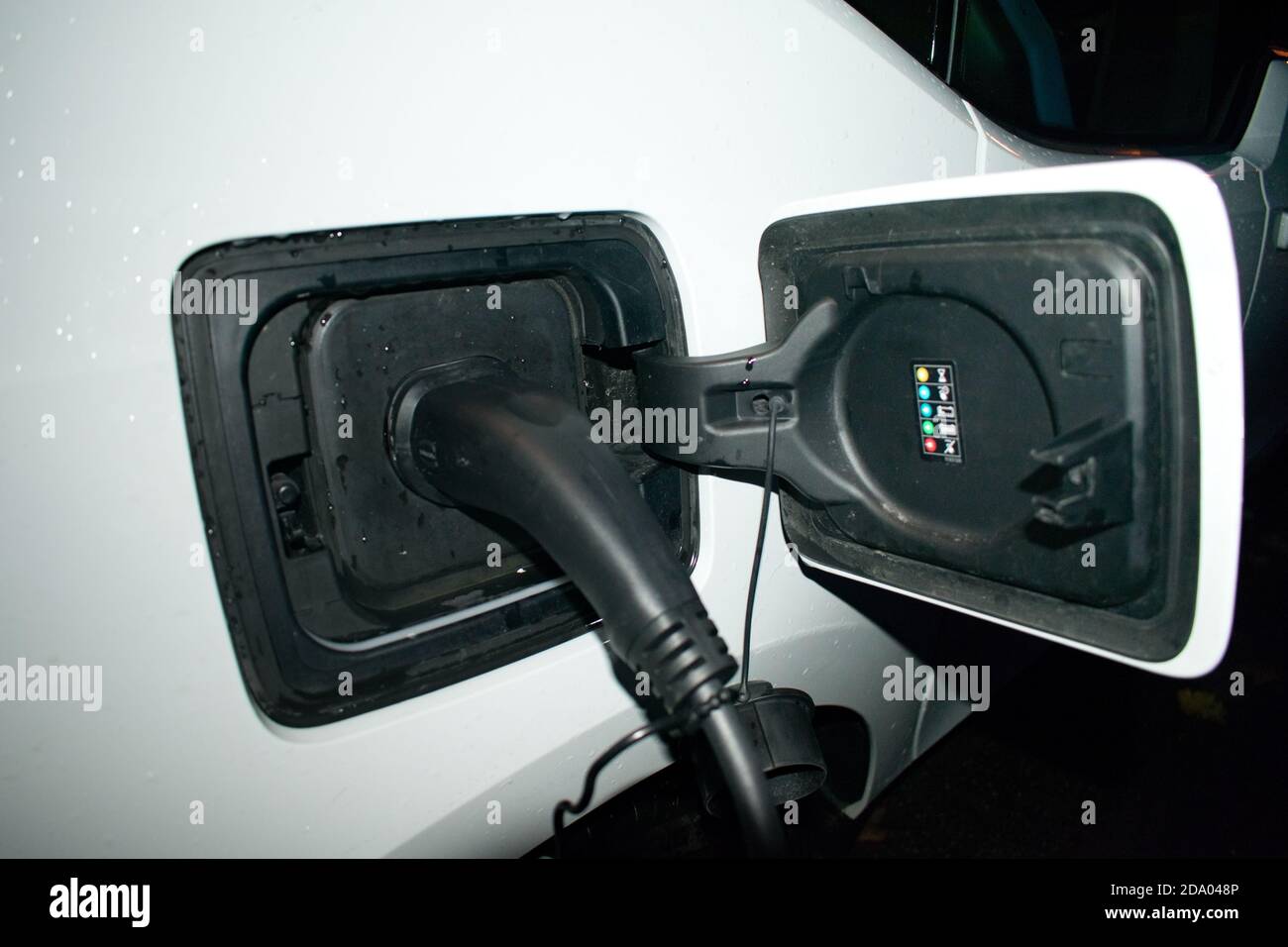 Elektroauto-Ladegerät zu Hause - Aufladen EV in der Nacht Mit Wandladegerät Stockfoto