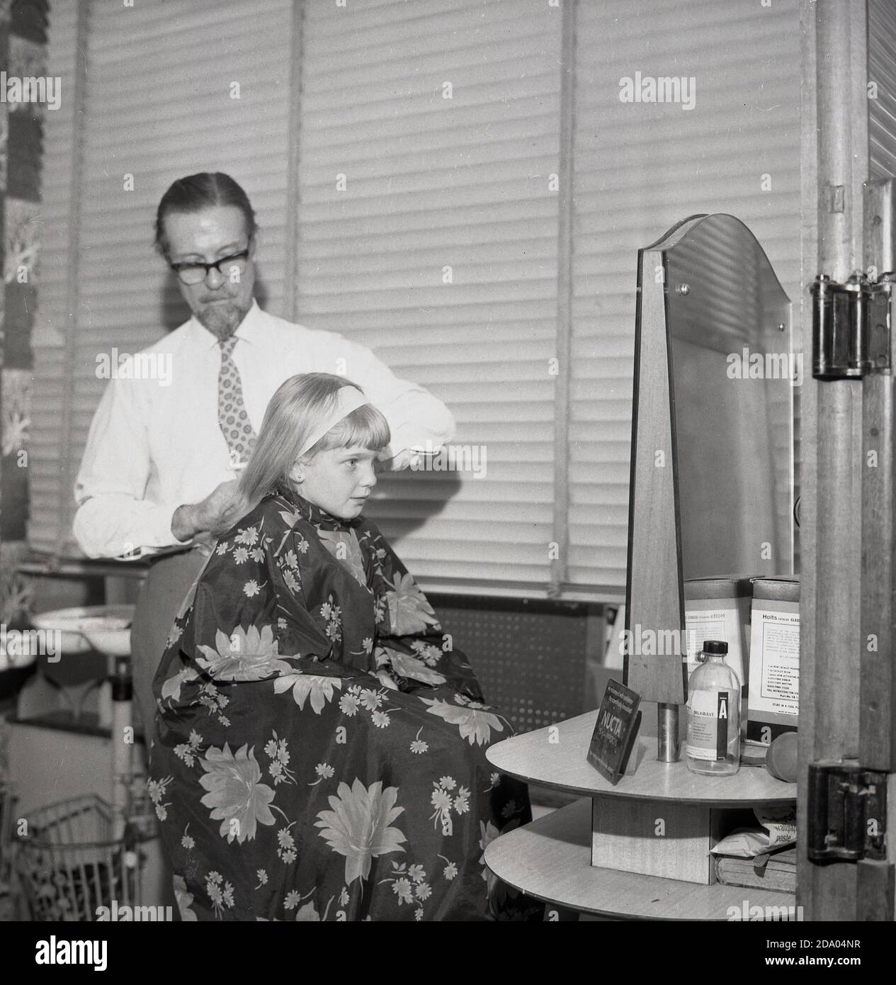 1960s, historisch, ein junges Mädchen in einem professionellen Friseursalon, das einen Haarschnitt von einem männlichen Friseur, London, England, Großbritannien, erhält. Stockfoto