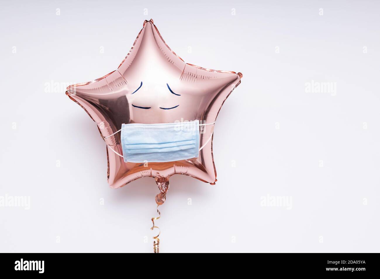 Sternförmige Folienballon mit einer medizinischen Maske und Doodle Traurige Augen Stockfoto