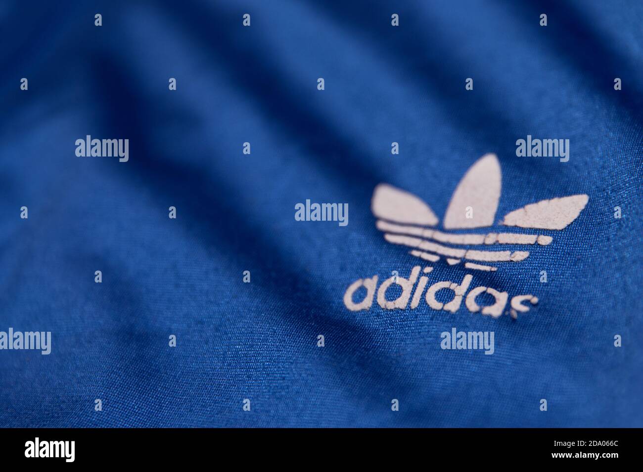 Getragenes weißes Adidas Trefoil Logo auf einer blauen Sportjacke Stockfoto