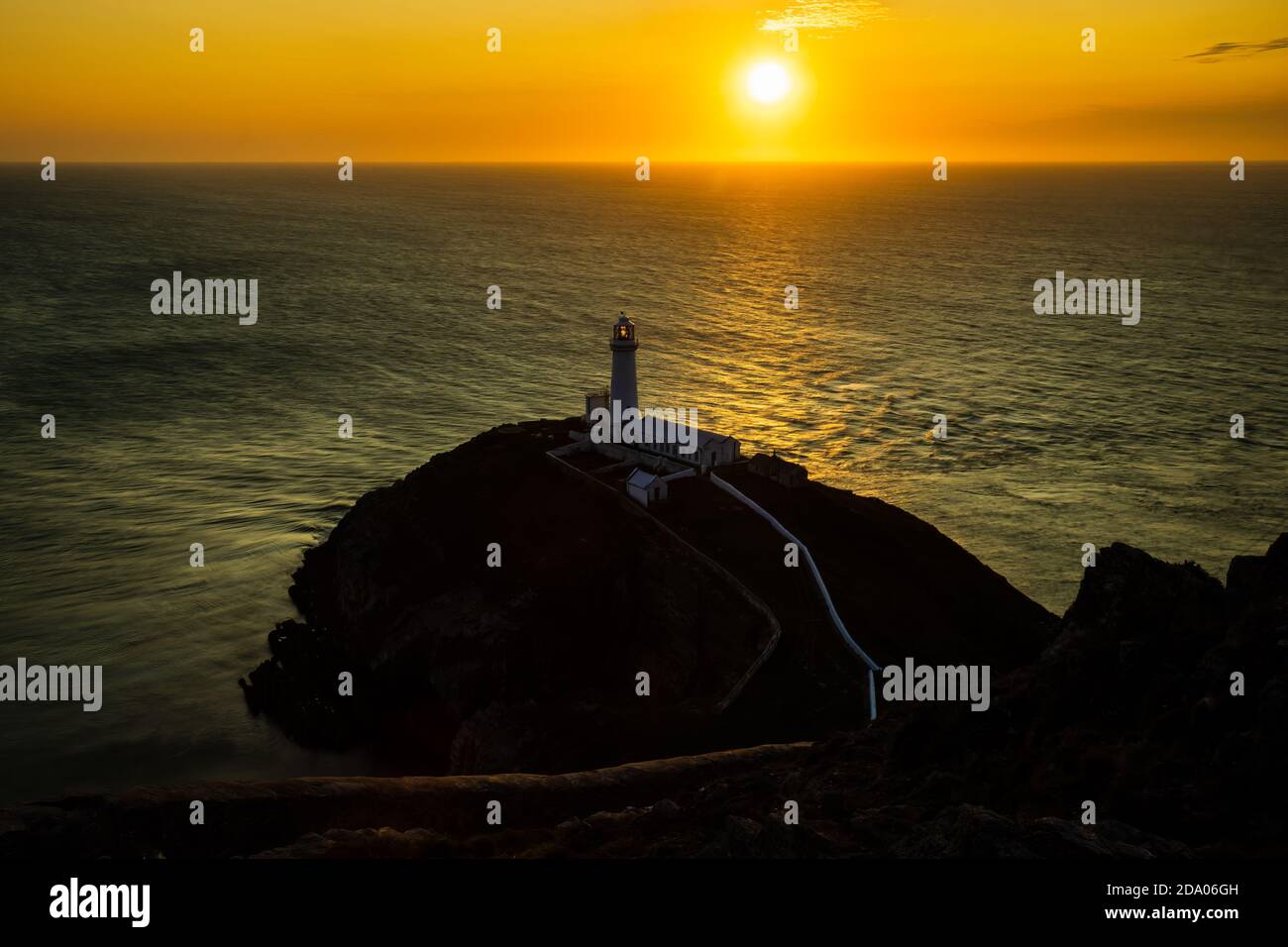 Ein Leuchtturm auf Klippen mit Sonnenuntergang über dem Meer (South Stack Lighthouse, Wales, UK) Stockfoto