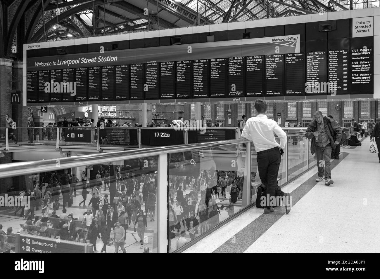 Pendler liest Abfahrtstafeln warten auf seinen Zug in Liverpool Street Station Stockfoto