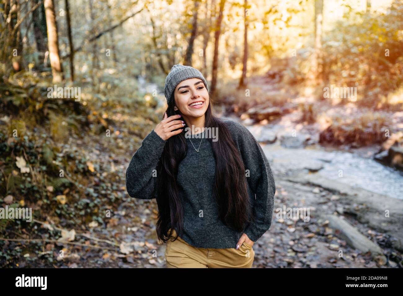 Sehr schöne und glückliche Frau in der Herbstsaison berührend Ihr Haar und durch einen Wald mit den Blättern gehen Der orangefarbenen und gelben Bäume und Stockfoto
