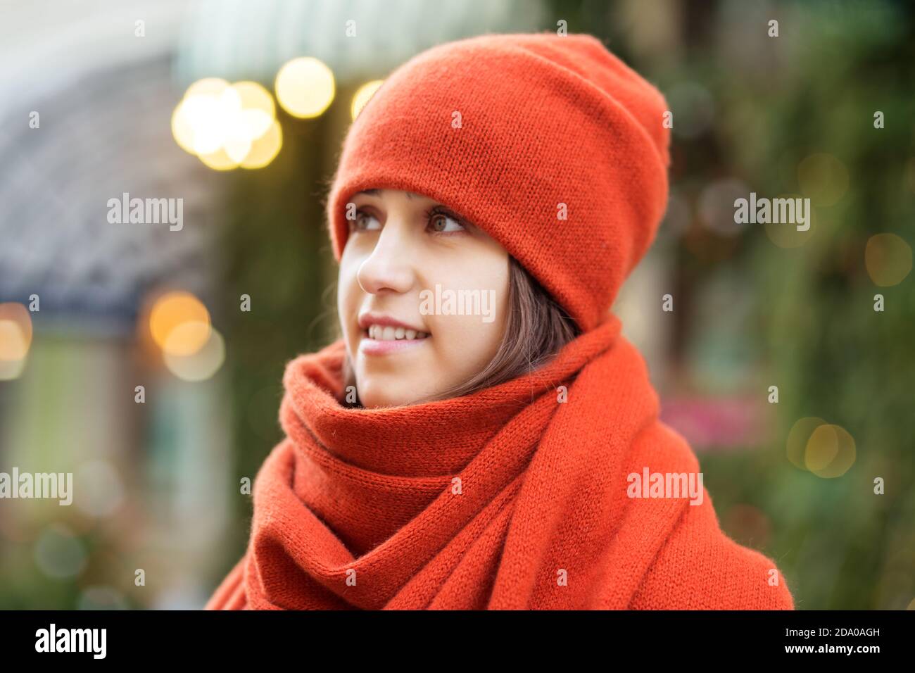 Porträt eines Mädchens in rotem Hut und Schal, Spaziergang durch die Weihnachtsstadt, ein Lächeln im Gesicht, kühles Wetter, ein faszinierender Blick Stockfoto