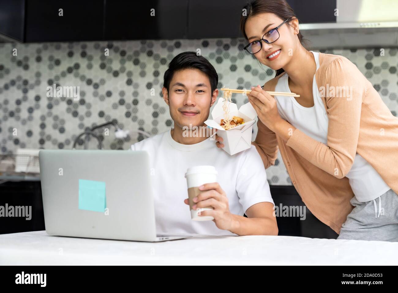 Asiatische Paar arbeiten von zu Hause in der Küche mit Lieferung Essen mitnehmen, während Stadt Lockdown von Coronavirus covid-19 Pandemie. Neue normale Lebensweise w Stockfoto