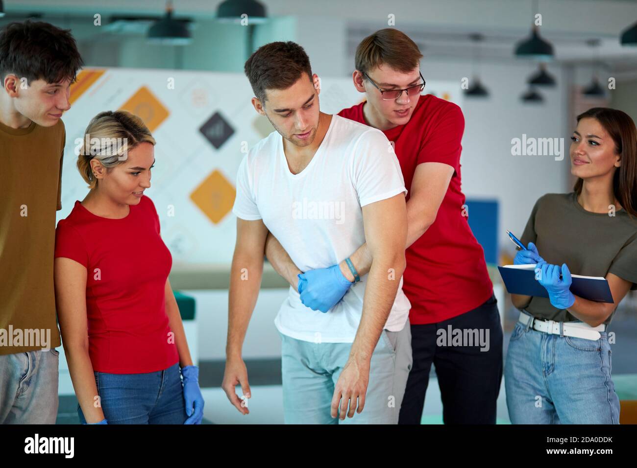 Professioneller kaukasischer Mannausbilder zeigt, wie man ein Leben sicher, wenn der Mensch erstickt ist, steht zurück und macht heimlich manövrieren beim erste-Hilfe-Training in Innenräumen Stockfoto