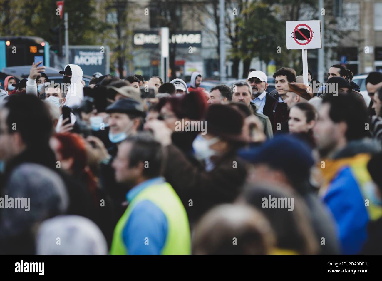 Bukarest, Rumänien - 8. November 2020: Während einer politischen Kundgebung zeigen die Menschen Gesichtsschutzmasken mit Transparenten. Stockfoto