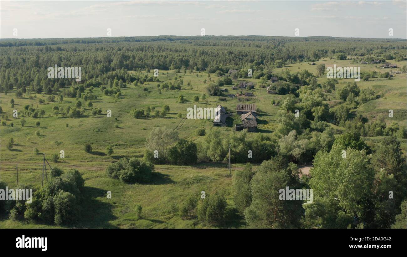 Das russische Dorf aus der Höhe. Traurige russische Sommerdorf Landschaft. Die Häuser in einem verlassenen Dorf sind mit Gras bewachsen. Stockfoto