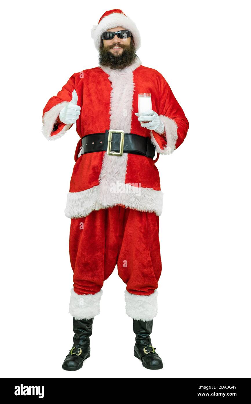 Arabischer Weihnachtsmann mit schwarzem Bart hält Milchglas, zeigt Daumen Finger nach oben. Der Weihnachtsmann hält ein Glas Milch auf weißem Hintergrund. Weihnachten steht bevor Stockfoto