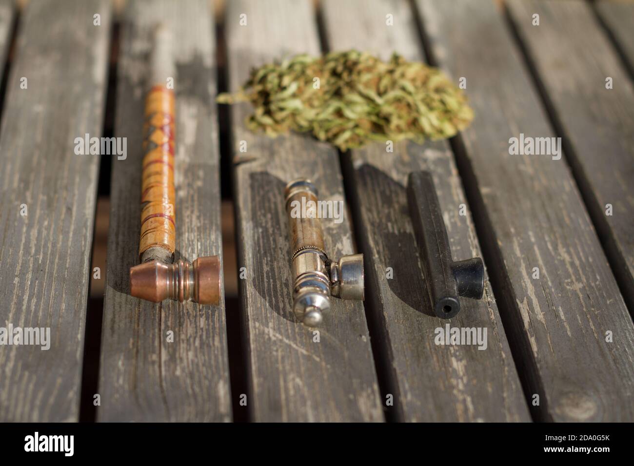 Anordnung von Rauchpfeifen mit Marihuanaknospe im Hintergrund. Stockfoto