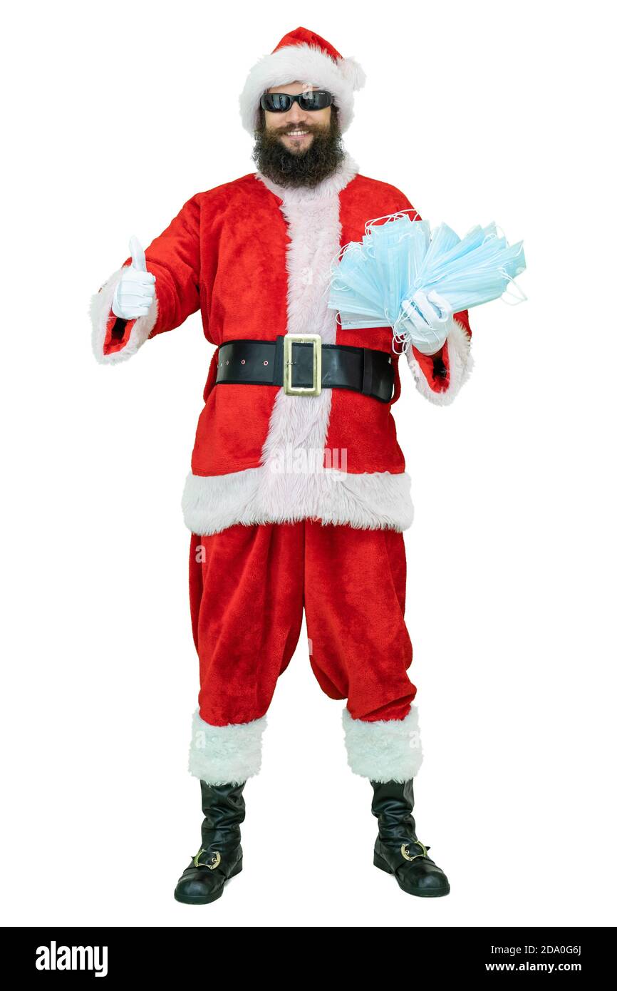 Santa Claus hält covid medizinische Maske. Junge arabische Santa zeigt Daumen Finger nach oben Stockfoto