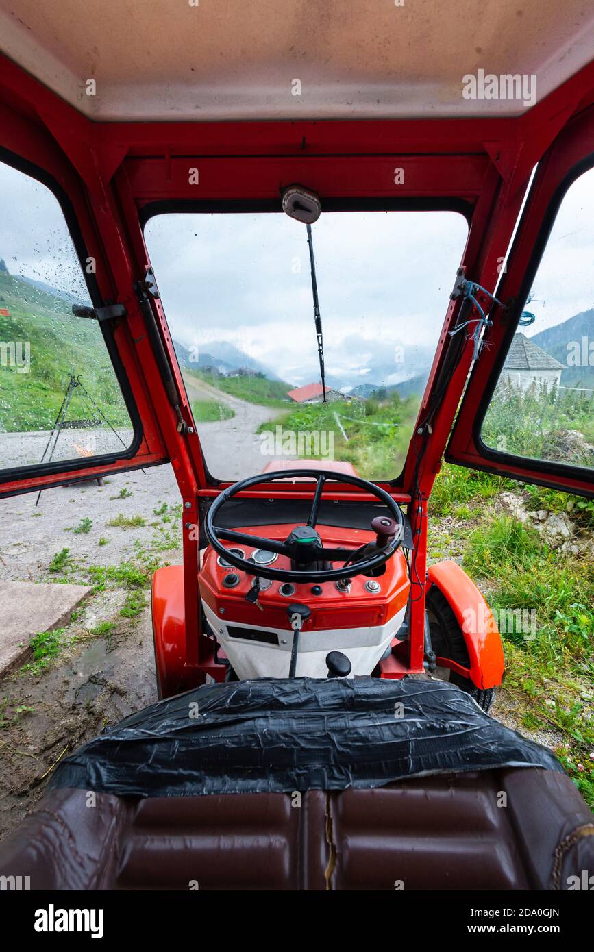 Blick über das Lenkrad von der Fahrerkabine eines Linder Traktors auf die Ackernalm und die Kaisergebirge, Tirol, Österreich Stockfoto