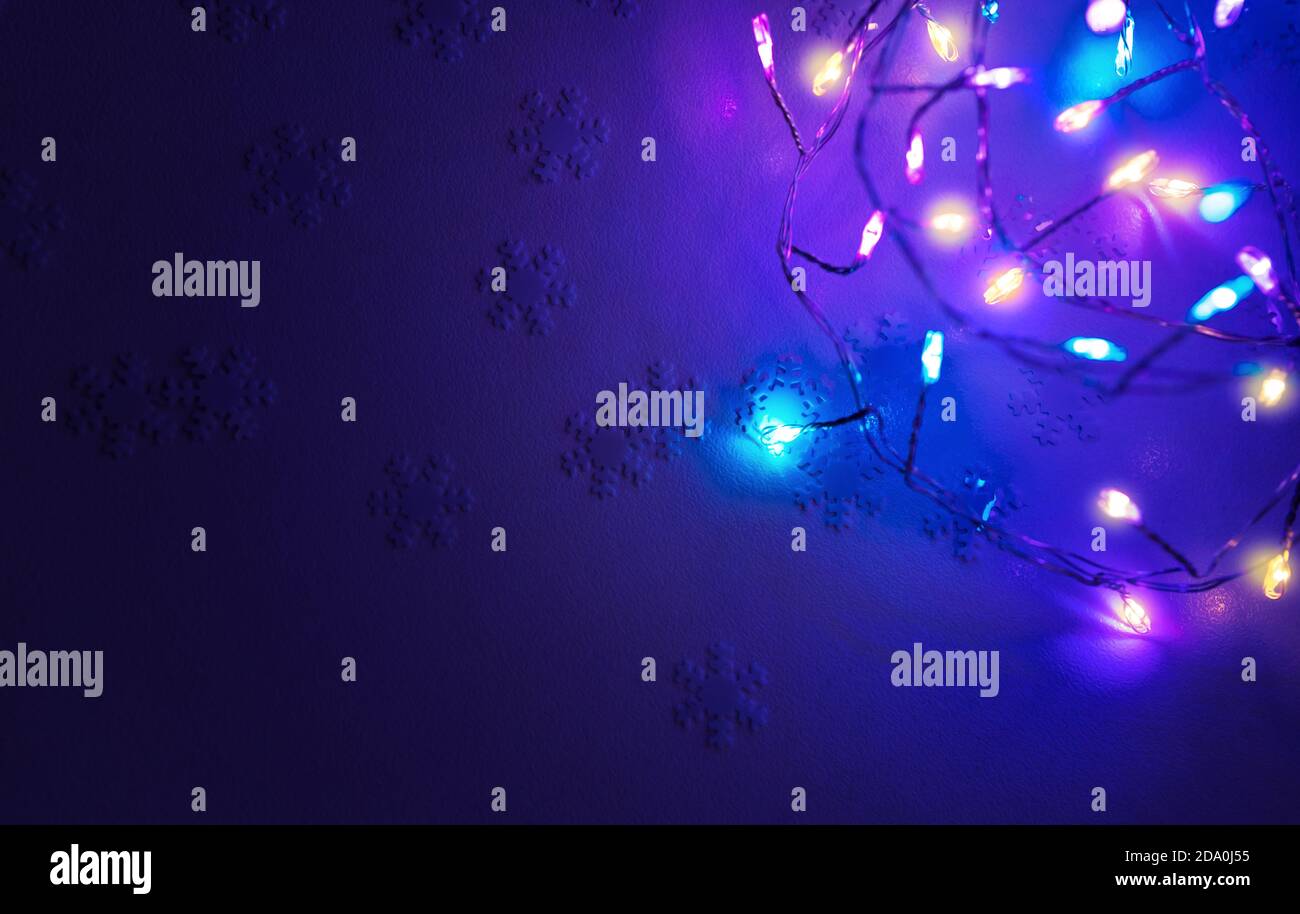 Weihnachten Hintergrund. Schneeflocke Konfetti und glühende Festoon auf blauem Hintergrund, Festliche Grußkarte, schöne Dekoration für Neujahrsfeier. Stockfoto
