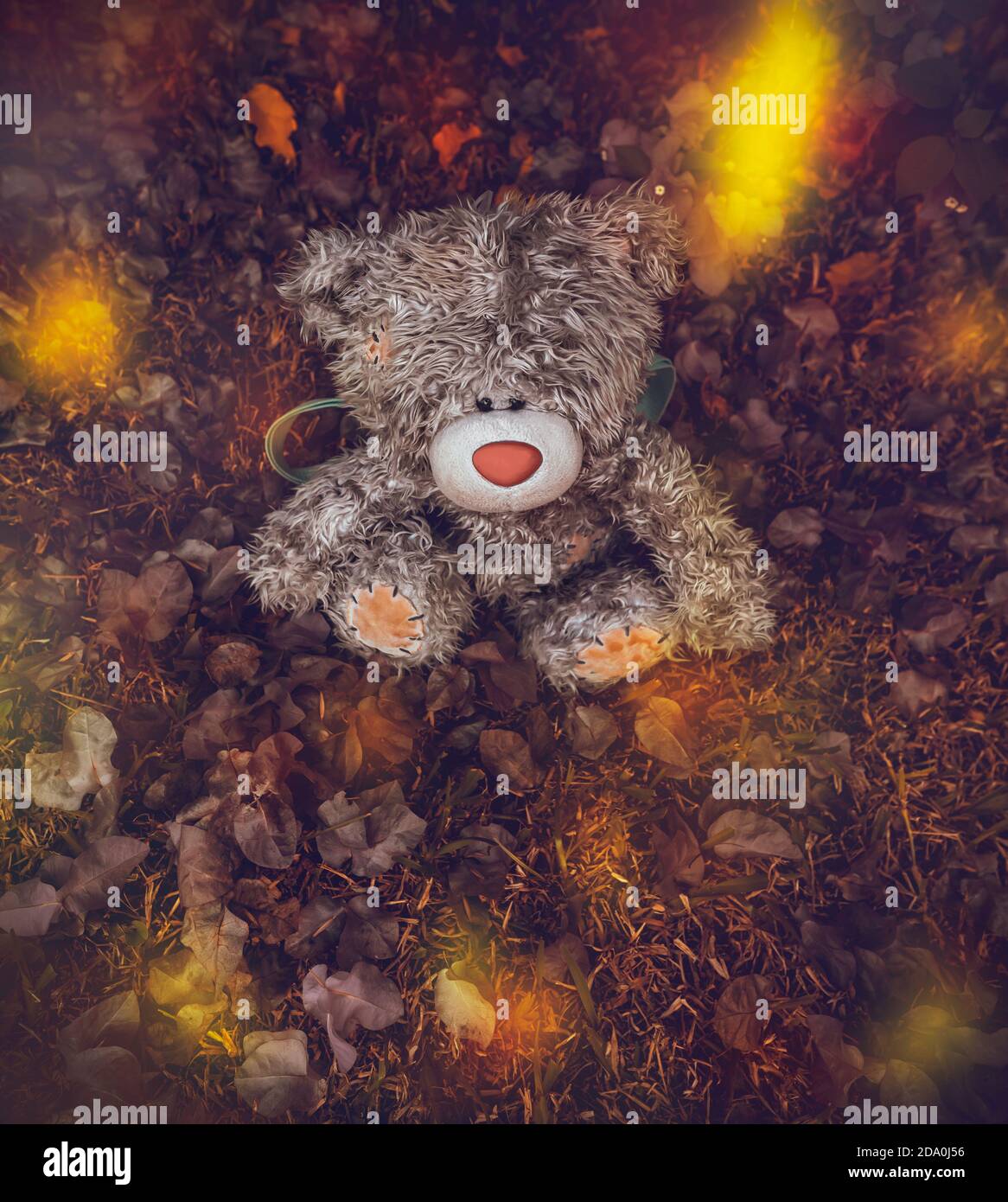 Konzeptuelles Foto einer ausgehenden Kindheit. Weggeworfen oder verloren Teddybär liegend auf dem Boden mit trockenen Baumblättern bedeckt. Herbststimmung. Stockfoto