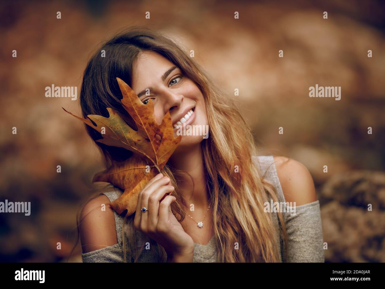 Porträt eines schönen Mädchen mit Spaß im Herbstwald. Halten in Hand trockenes Ahornblatt. Die Schönheit der Herbstsaison. Stockfoto