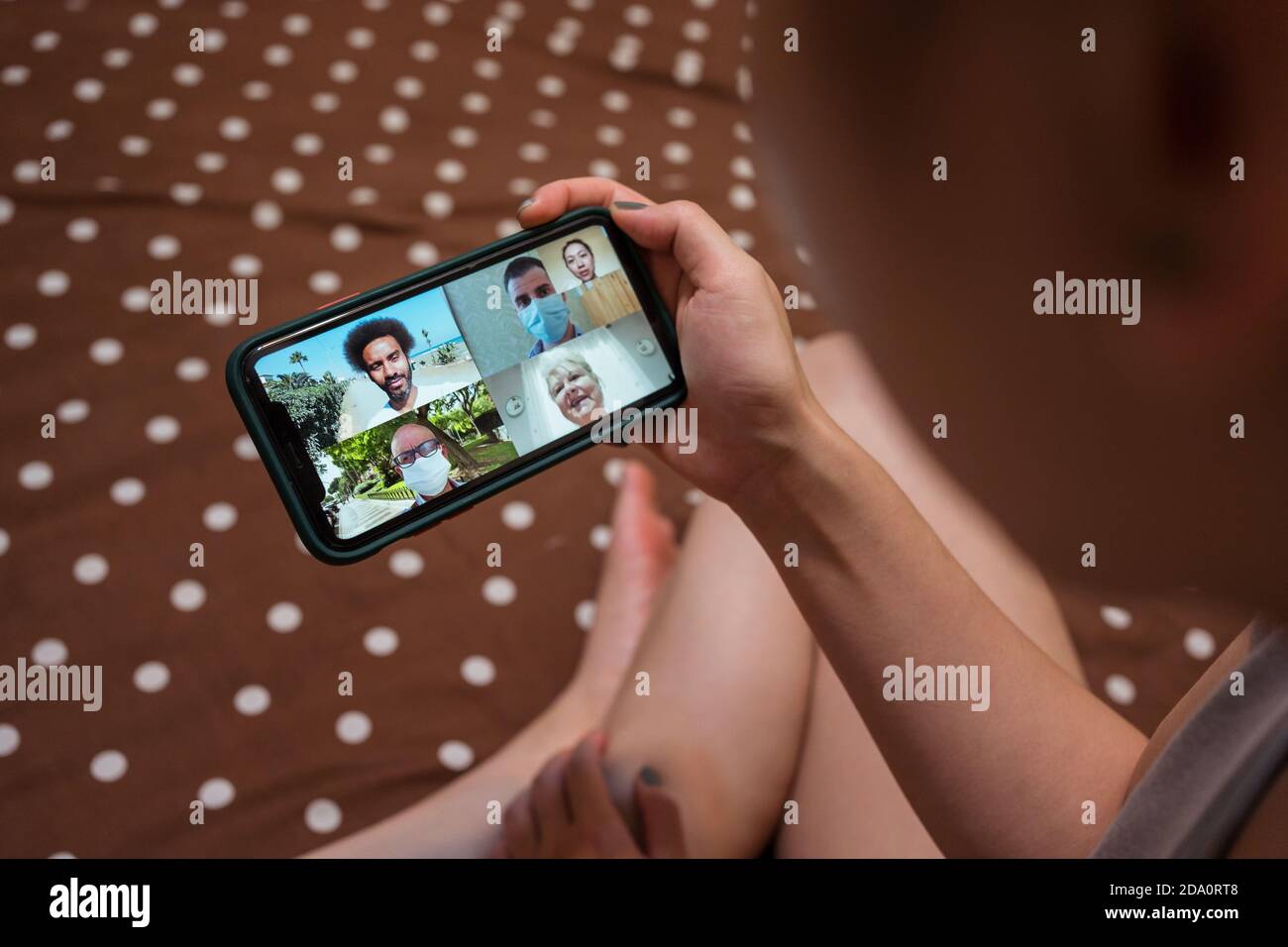 Von oben junge asiatische weibliche Kommunikation online per Video-Chat Auf dem Handy während der Ruhe im Bett während Coronavirus Epidemie Stockfoto