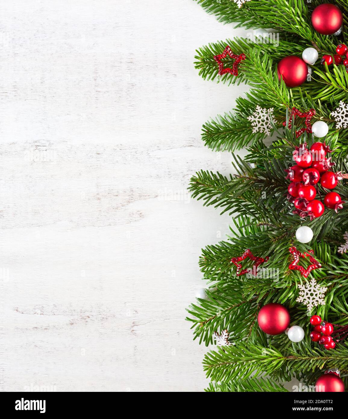 Weihnachtliche Bordüre mit Tannenzweigen und Kugeln auf weißem, schäbigen Holzbrett mit Platz für Text. Flach liegend. Hintergrund zu Neujahr. Stockfoto