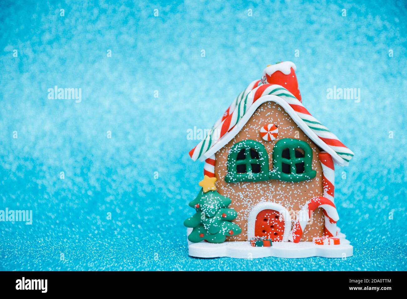 Weihnachtsspielzeug in Form eines Lebkuchenhauses auf einem blau glänzenden Hintergrund mit Copyspace. Selektiver Fokus. Stockfoto