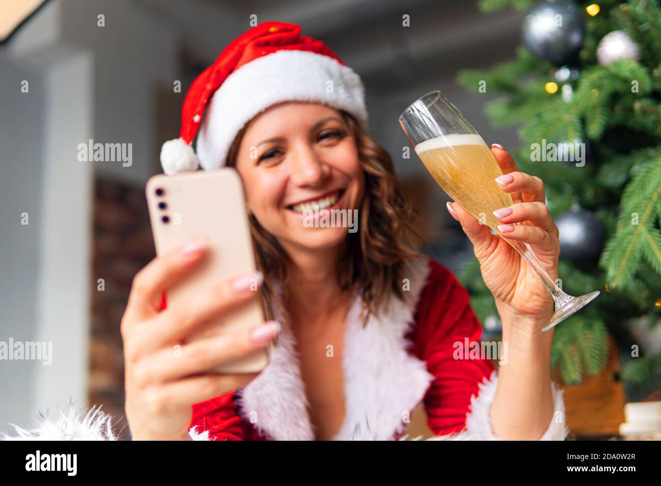 Geschlossen schöne Frau Hut und roten Weihnachtsmann lächelnd glücklich, Champagner Glas, Konzept Urlaub feiern, Weihnachtsbaum Hintergrund. Weihnachten Stockfoto