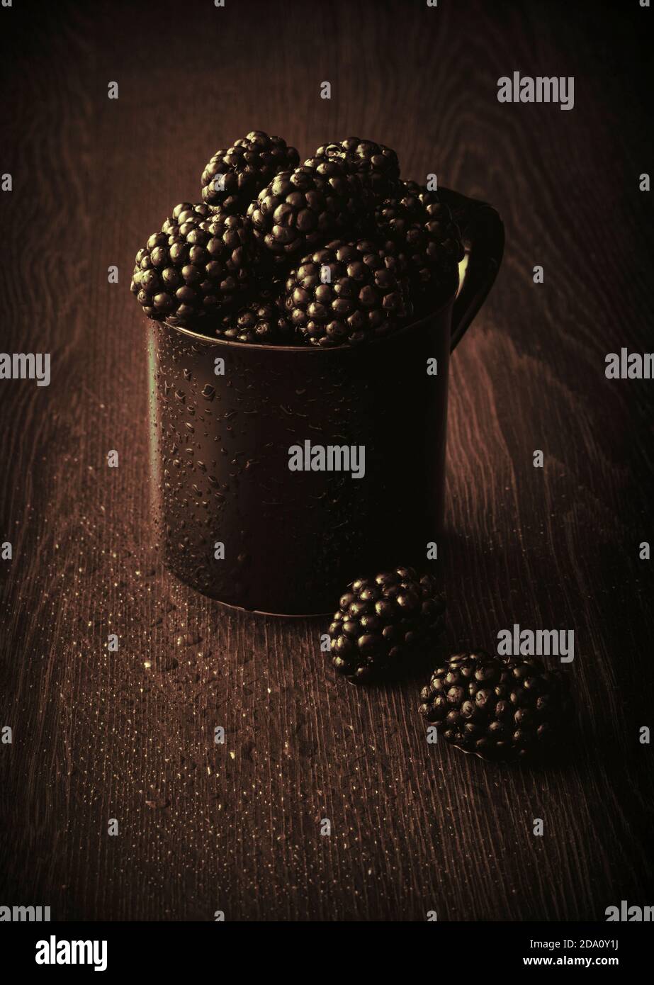 Frische saftige Brombeeren in schwarzem Becher mit Textur-Overlay Stockfoto