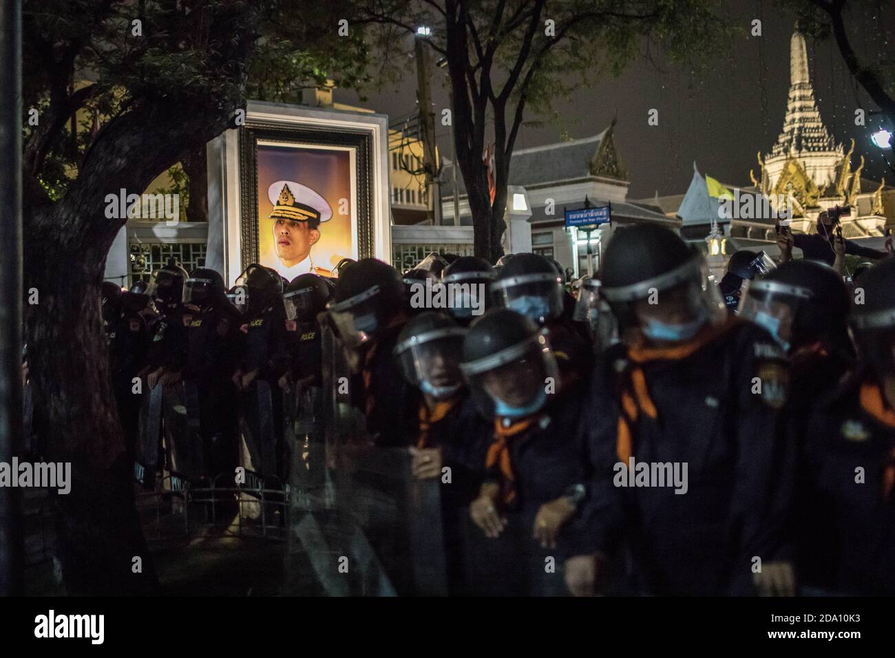 Bangkok, Thailand. November 2020. Polizeibeamte der Riot-Polizei, die neben einem Porträt des thailändischen Königs Maha Vajiralongkorn (Rama X) während einer regierungsfeindlichen Demonstration in der thailändischen Hauptstadt gesehen wurden. Prodemokratische Demonstranten gingen auf die Straßen am Democracy Monument, um in Richtung des Großen Palastes zu marschieren, um dem thailändischen König Maha Vajiralongkorn (Rama X) einen Brief zu überbringen. Die Demonstranten wurden von der thailändischen Polizei getroffen, die Stadtbusse und Stacheldraht benutzte, um die Straße zu blockieren. Und Wasserkanonen, um die Menge in Sanam Luang vor dem Großen Palast zu zerstreuen. Kredit: SOPA Images Limited/Alamy Live Nachrichten Stockfoto