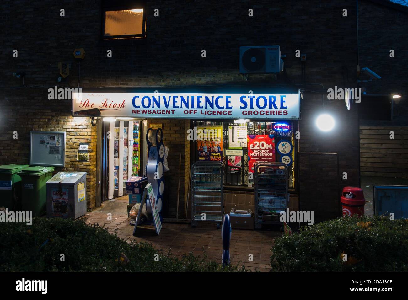 Ein 24-Stunden-Geschäft in einem Häuserblock am frühen Abend Bei eingeschalteter Beleuchtung Stockfoto