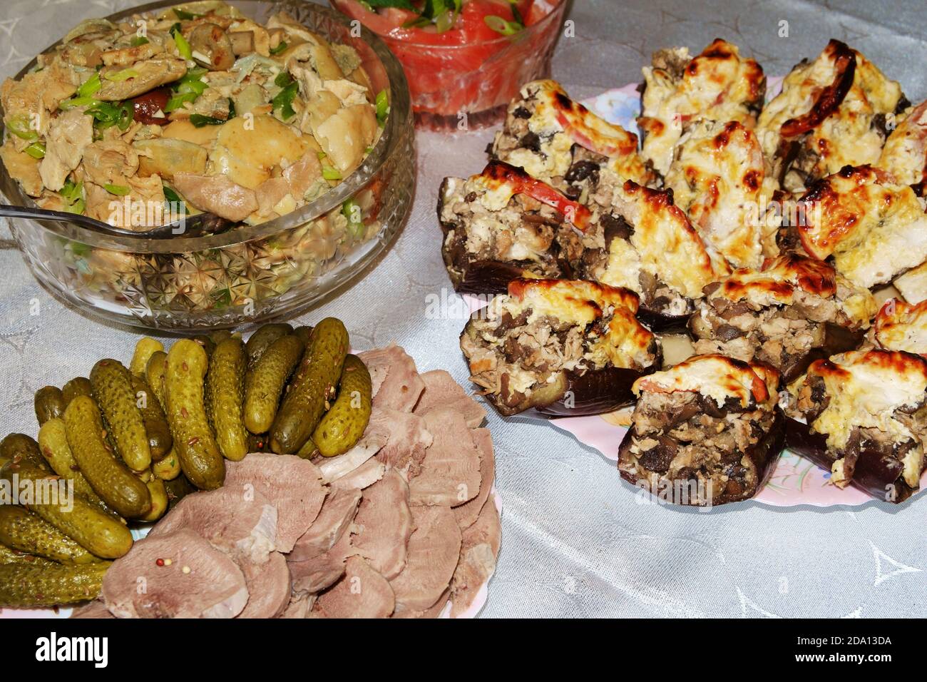Festlicher Tisch. Gekochte Schweinefleisch Zunge mit Gurken und Gewürzen, gesalzene Pilze gewürzt mit Kräutern, gefüllte Aubergine. Selektiver Fokus. Stockfoto