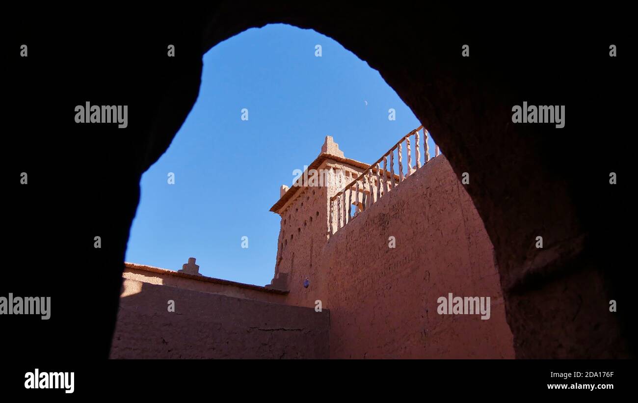 Blick auf die Spitze einer historischen Berber Kasbah (Kasbah) durch ein Tor mit einem Turm aus Lehm und Stroh Material in der Nähe von Skoura, Marokko, Afrika gebaut. Stockfoto