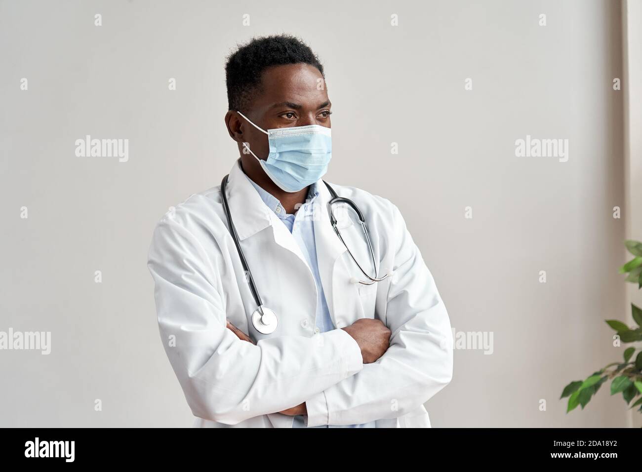 Afrikanisch schwarz männlich Arzt trägt Gesichtsmaske weg suchen isoliert auf weiß. Stockfoto