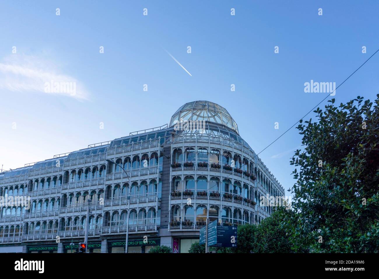 St Stephens Green Shopping Centre in Dublin, Irland mit einem klaren blauen Himmel und über dem Flugzeug fliegt ein Flugzeug vorbei. Stockfoto