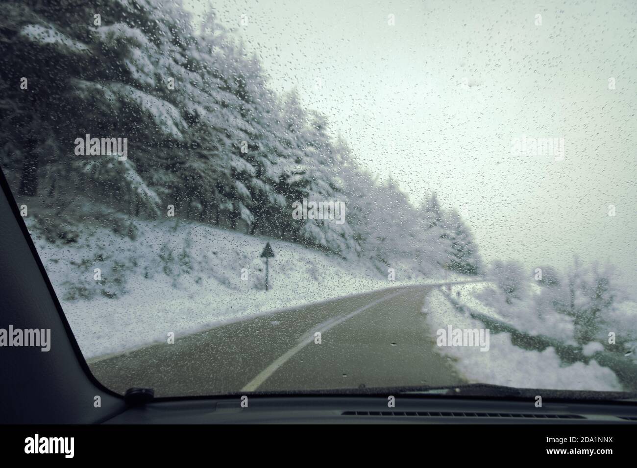 Verwischte Winterlandschaft durch die Windschutzscheibe des Autos bei einem Roadtrip im Nebrodi-Nationalpark, Sizilien, Italien (Schwerpunkt auf Wassertropfen) Stockfoto