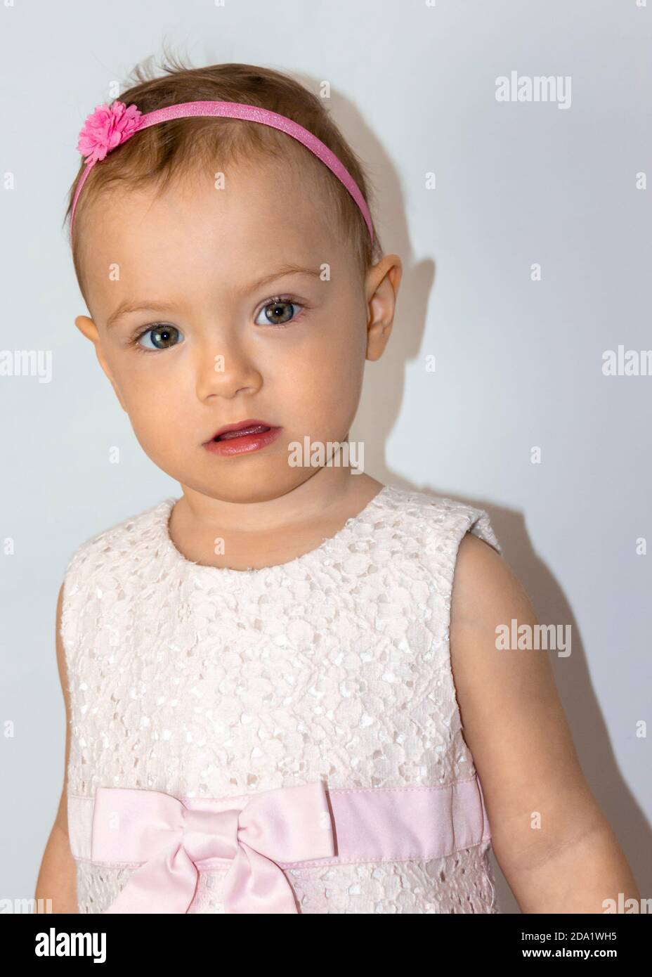 Sehr niedlich 20 Monate alt Kleinkind Porträt. Schöne 1.5 Jahre alte kleine Mädchen, posiert natürlich. Kind trägt niedliches rosa Kleid und Stirnband. Stockfoto