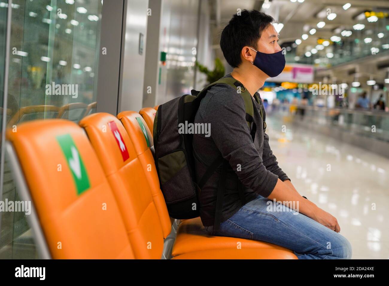 20s junge Erwachsene asiatische männliche Touristen Backpacker hält Flugticket trägt eine Gesichtsmaske mit einem Flugticket am Flughafen. Social Distancing Reise Sicherheit Beratung während Covid-19 Konzept Stockfoto