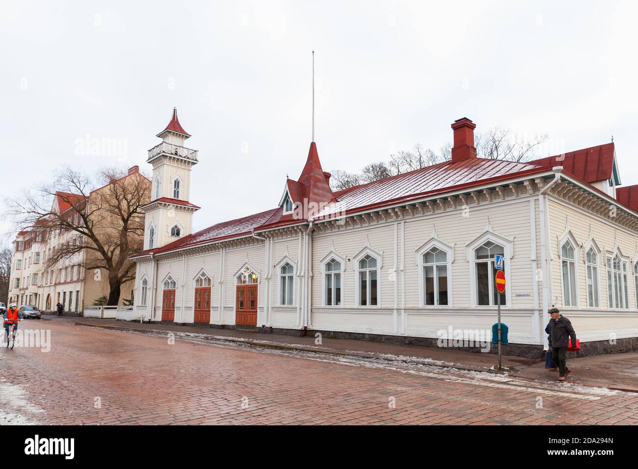 Kotka, Finnland - 14. Dezember 2014: Straßenansicht der Stadt Kotka am Wintertag. Gewöhnliche Menschen gehen die Straße in der Nähe von alten Holzhaus mit dekorativen Schlepptau Stockfoto