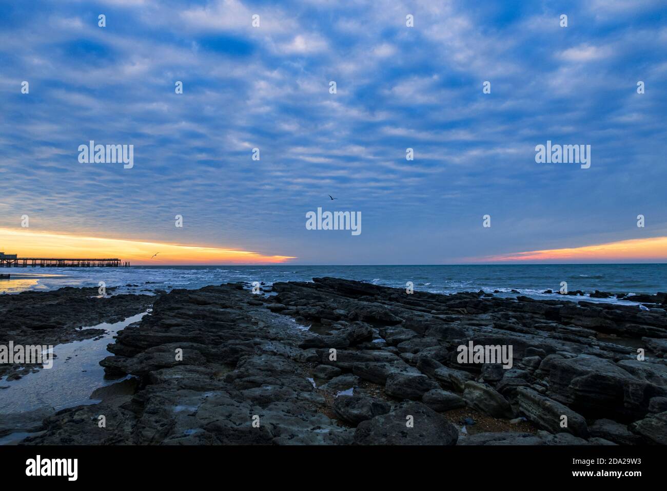 Dramatischer Makrelenhimmel im Morgengrauen über dem Hastings Pier in East Sussex südostengland Stockfoto