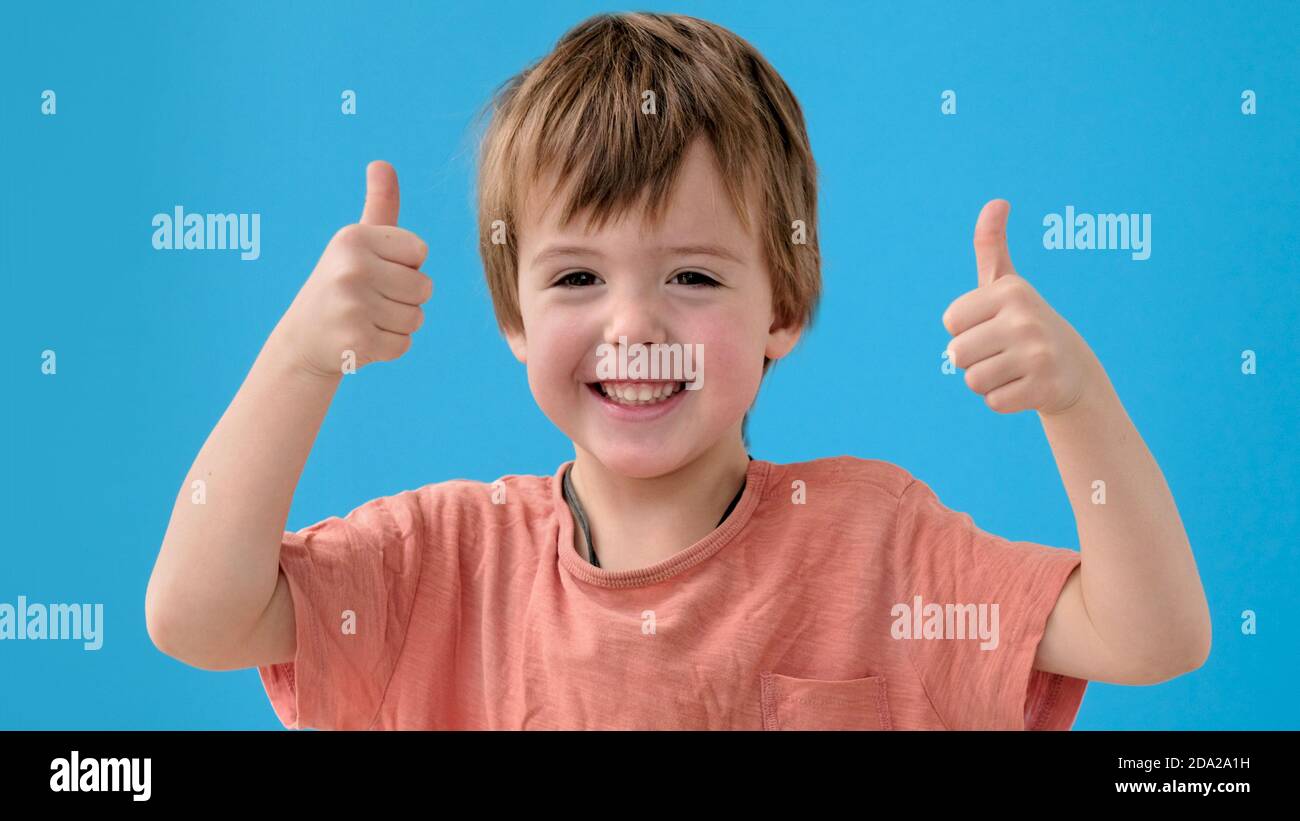 Lustiger Junge lächelt und zeigt Daumen-up posiert für Kamera Stockfoto