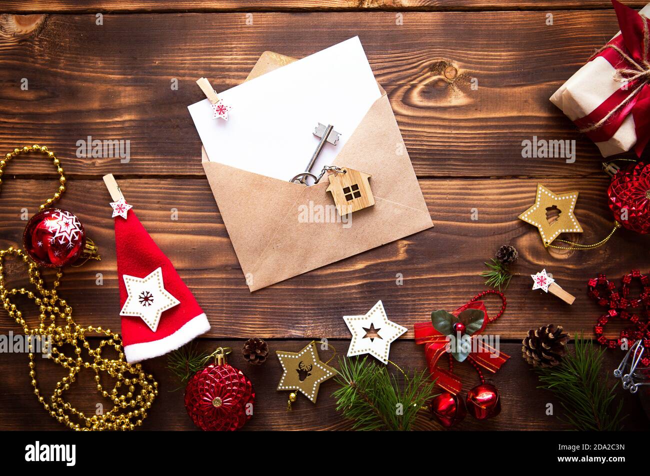 Weihnachtswohnung lag auf einem hölzernen Hintergrund mit Schlüsseln zu neuem Haus in der Mitte mit einem Umschlag mit einem Zettel. Neues Jahr, Übertragung, Aktien der Mo Stockfoto