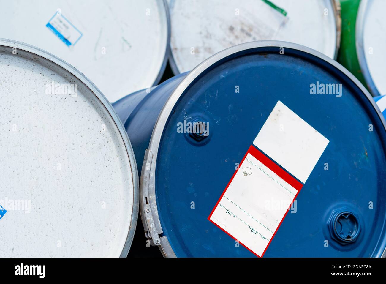 Selektiver Fokus auf alte Chemiefässer. Blaue Ölfass. Stahlöltank. Lager für giftige Abfälle. Gefahr Chemikalienfass mit Warnschild. Industrie. Stockfoto