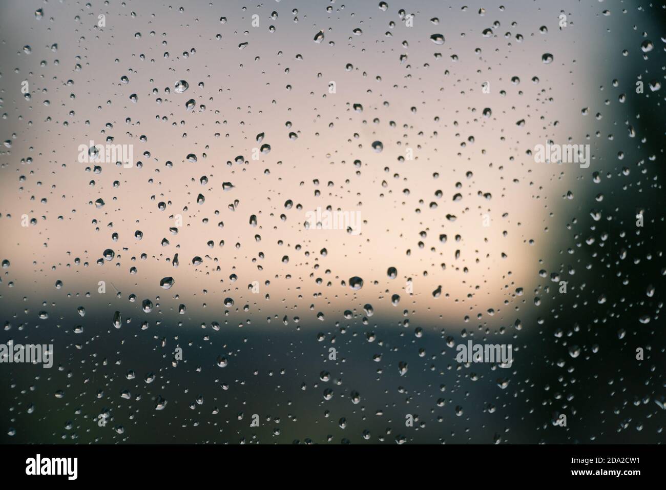 Wasser tropft nach Regen auf das Fensterglas. Makro von Regentropfen als abstrakter Hintergrund mit geringer Schärfentiefe. Regnerisches Wetter, melancholische Stimmung. Stockfoto