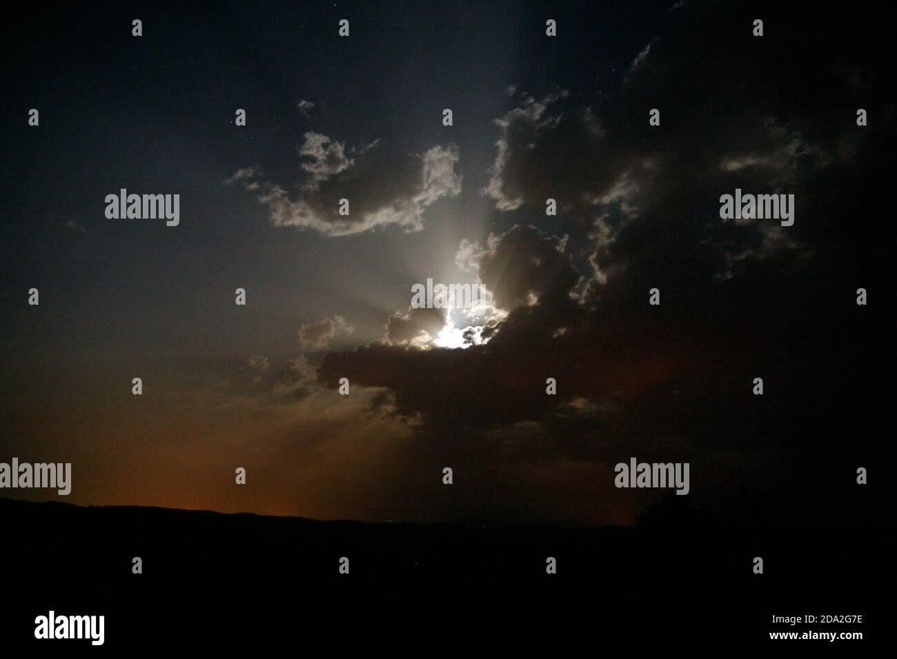 Die Sonne scheint hinter einer dunklen Wolkenwand im Himmel Stockfoto