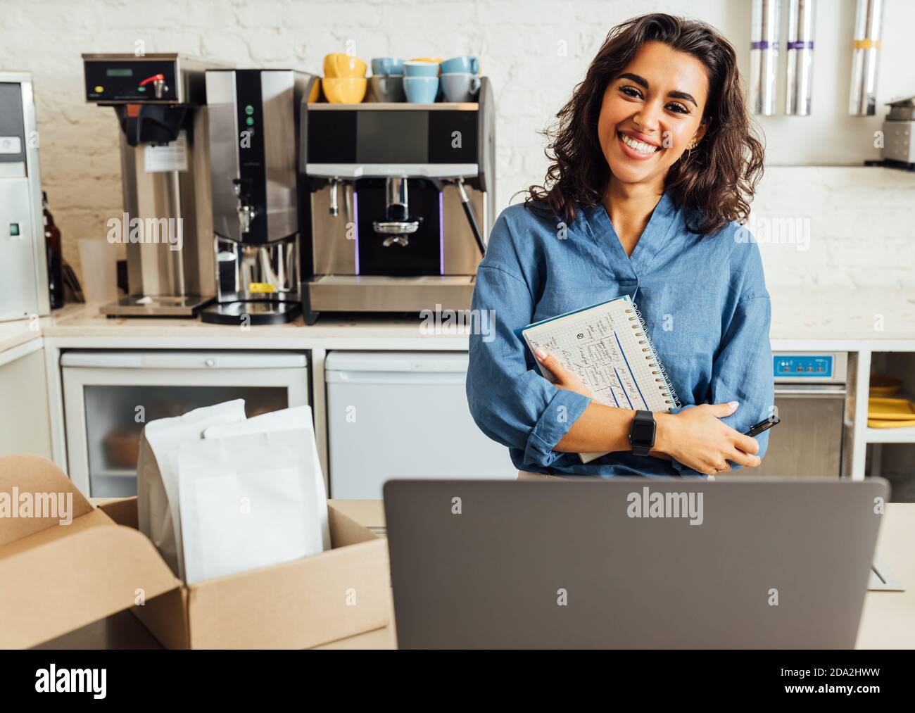 Porträt einer glücklichen weiblichen Café-Besitzerin. Geschäftsfrau hält ein Notebook im Café und schaut auf die Kamera. Stockfoto