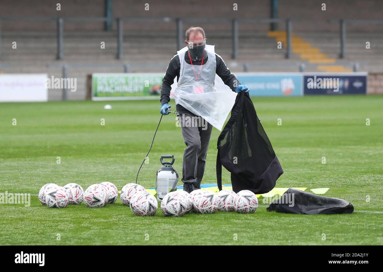 Ein offizieller PSA-Träger sprüht Fußbälle mit Desinfektionsmittel-Spray vor der ersten Runde des Emirates FA Cup zwischen Torquay United und Crawley Town in Plainmoor, Torquay. Picture James Boardman / Tele-Bilder Stockfoto